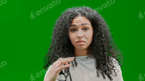 Preview: Young and beautiful African American woman staring at the camera in front of a green wall