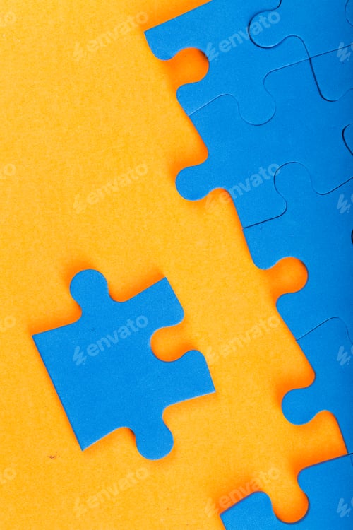 Preview: Bright blue puzzle pieces on a vibrant orange background waiting to be assembled