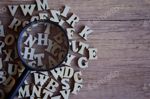 Preview: Magnifying glass with scattered alphabet letters on the table.