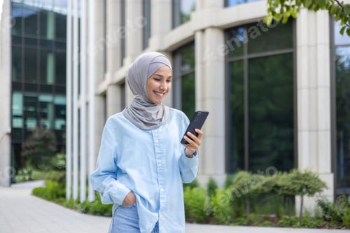 Preview: A young beautiful business woman in a hijab walks through the city, a Muslim woman holds a phone in