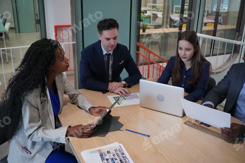 Preview: Image of young businessmen and colleague discussing document in laptop and touchpad at meeting