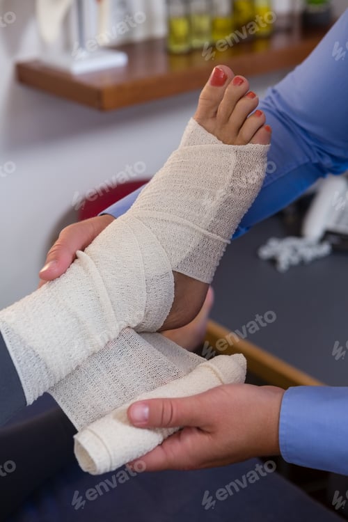 Preview: Physiotherapist putting bandage on injured feet of patient
