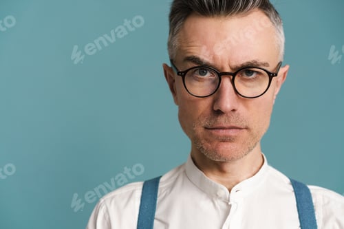 Preview: Displeased grey-haired man in eyeglasses posing and looking at camera