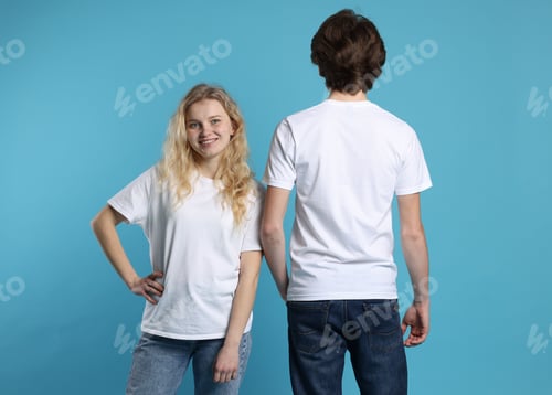 Preview: Young woman and man wearing blank white t-shirts on light blue background. Mockup for design