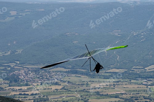 Preview: Hang gliding pilot soaring over french countryside: aerial view of freedom and adventure