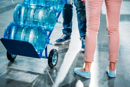 Preview: cropped view of woman standing next to courier delivering water