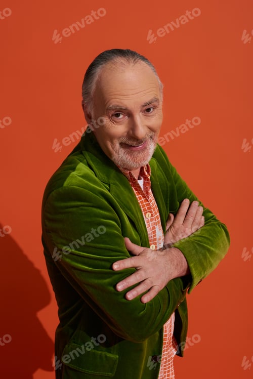 Preview: optimistic and charismatic bearded senior man standing with folded arms and smiling at camera