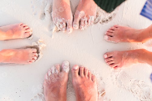 Preview: Close-up of the feet of family on the white sandy beach