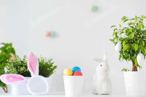 Preview: Colored eggs, cute little bunny and rabbit ears on the table on Easter day. Celebrating Easter
