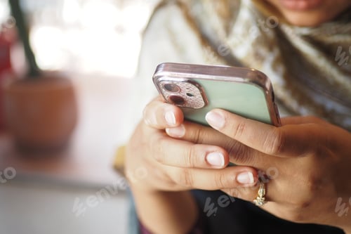 Preview: Woman using smartphone while relaxing indoors in a cafe
