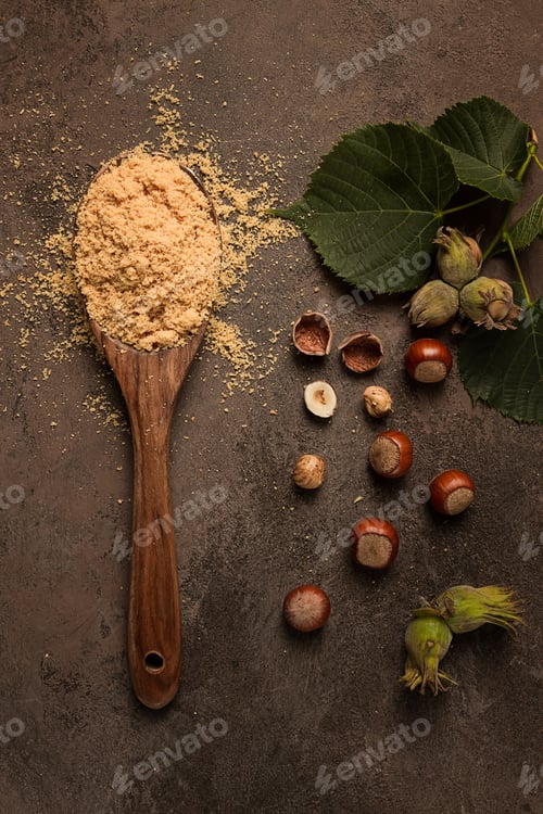 Preview: wooden spoon, with hazelnut flour, on a brown table, top view, no people,