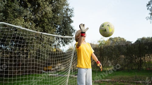 Preview: Kid goalkeeper catching soccer ball during outdoor play
