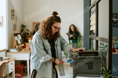Preview: Young Adult Caucasian Woman Using Printer in Modern Office Environment