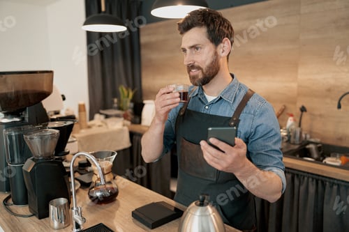 Preview: barista drinking coffee and holding phone during lunch break