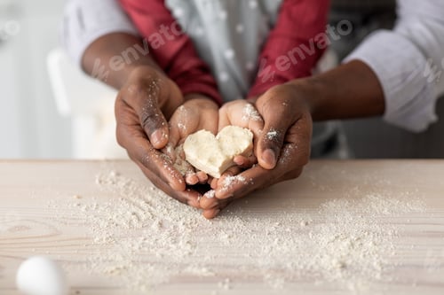 Preview: Hands of black father and daughter holding heart shaped cookies