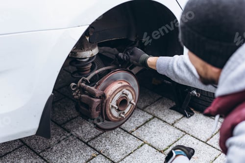 Preview: Man replacing his car tire with winter tires using a wrench, preparing for the cold weather