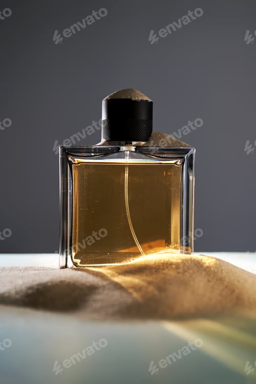 Preview: A bottle of perfume on a background of sand.