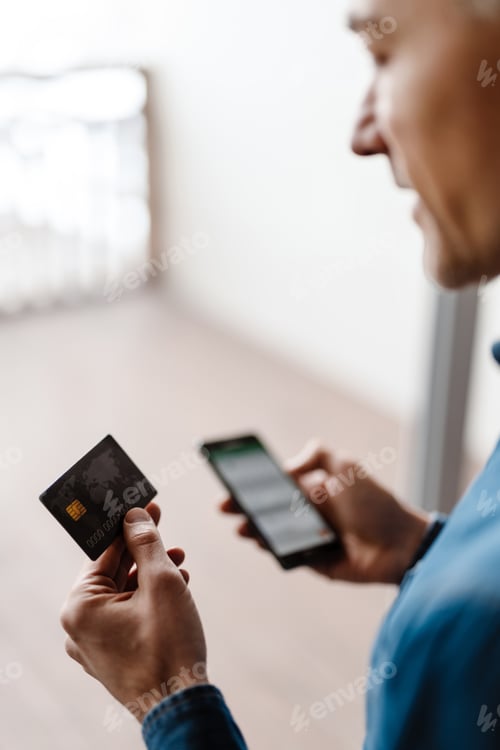 Preview: Mid aged casual man holding mobile phone