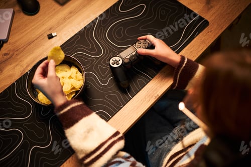 Preview: Young Adult Caucasian Woman Eating Chips While Playing Video Game Indoors
