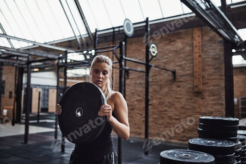 Preview: Fit young woman selecting weights for a gym workout