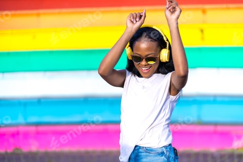 Preview: Joyful african woman with headphones dancing in an urban park
