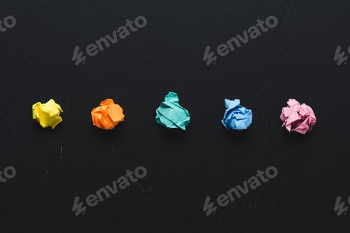 Preview: top view of colorful crumpled paper balls on black background, think different concept
