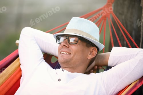Preview: Man resting in comfortable hammock at green garden