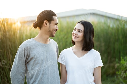 Preview: Young couple standing outdoor in the evening sunset in the field with happiness