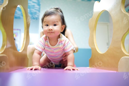 Preview: Young little smiling Asian baby enjoy playing in kid playground.