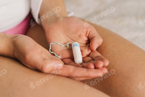 Preview: A woman in underwear holds a tampon in her hands.