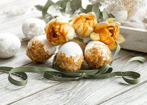 Preview: Cozy easter composition with eggs and flowers on wooden surface close up.