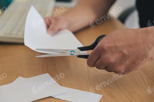 Preview: Left-handed man's hand cutting paper with