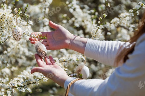 Preview: Woman Holding Feathered Easter Egg on Blooming Branch