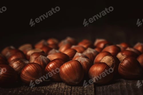Preview: close up view of hazelnuts on wooden surface on black background