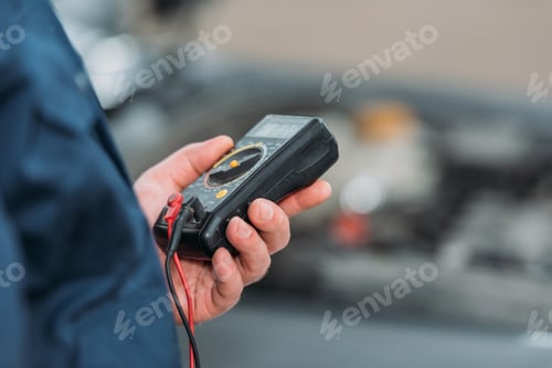 Preview: Cropped shot of automechanic using a digital multimeter in a service workshop.