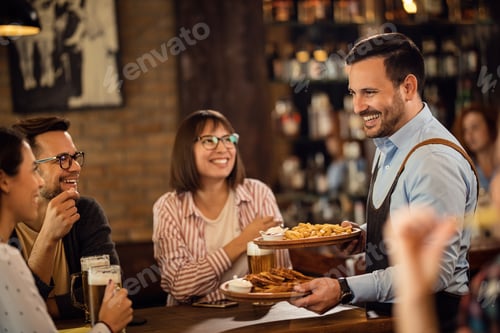 Preview: Happy waiter serving food to guest who are drinking beer in a pub.