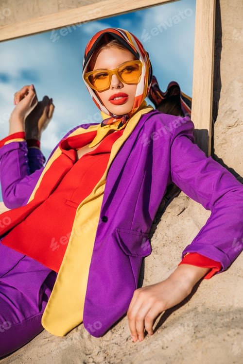 Preview: elegant fashionable lady posing on mirror on sand