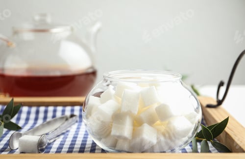 Preview: Refined sugar cubes in glass bowl and tongs on wooden tray