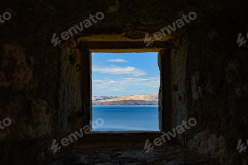 Preview: Minimalist image of window on old stone building overlooking sea.