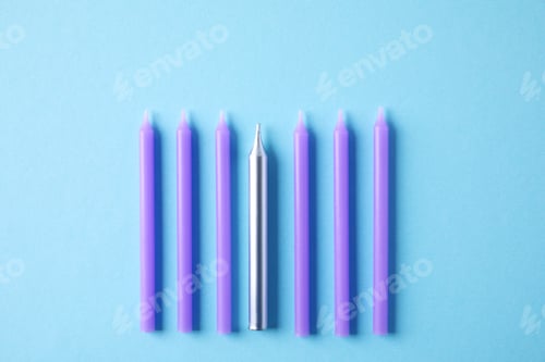 Preview: Bright birthday candles on light blue background, flat lay