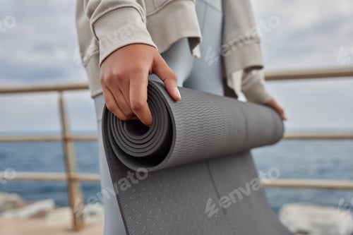 Preview: Adult Rolling Up Yoga Mat Near Ocean