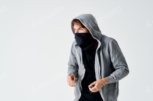 Preview: male hacker in a gray sweater stealing black mask on his face
