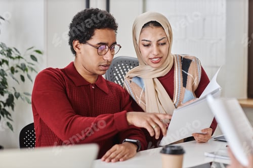 Preview: Two Arabian business people man and woman working together at meeting table