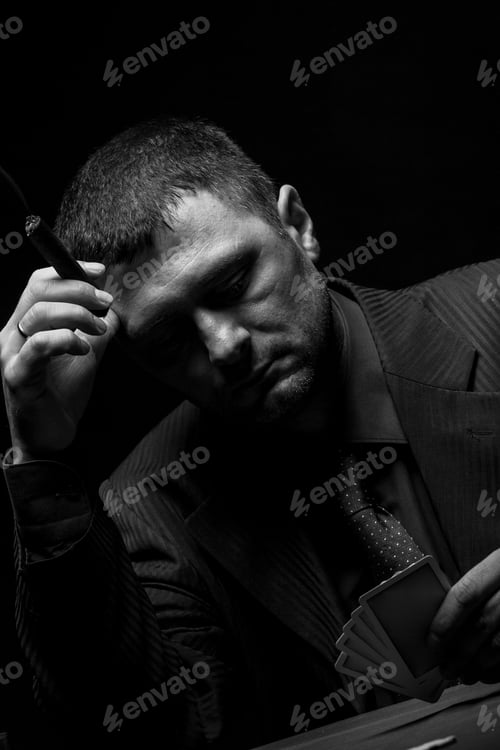 Preview: Studio shot of male gambler playing poker isolated on black background.