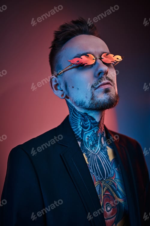 Preview: Tattoo artist male model posing in a neon studio with half-naked body, tuxedo and sunglasses.