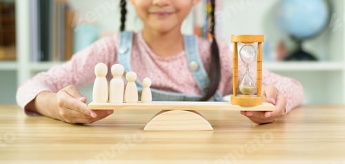 Preview: Unidentified little girl's hands trying to balance the family member model and hourglass on balance.
