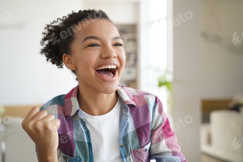Preview: Excited mixed race teen girl makes yes winner hand gesture, celebrates success, personal achievement