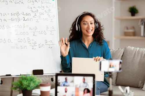 Preview: Smiling young woman teaching math to students online, waving hello