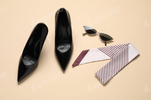 Preview: Pair of elegant black heels, sunglasses and scarf on beige background, flat lay. Stylish shoes