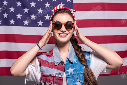 Preview: portrait of smiling stylish woman in sunglasses with american flag behind